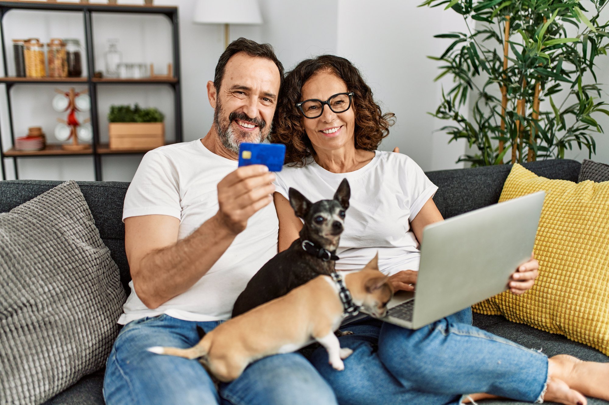 Couple at home holding a payment card while using a laptop