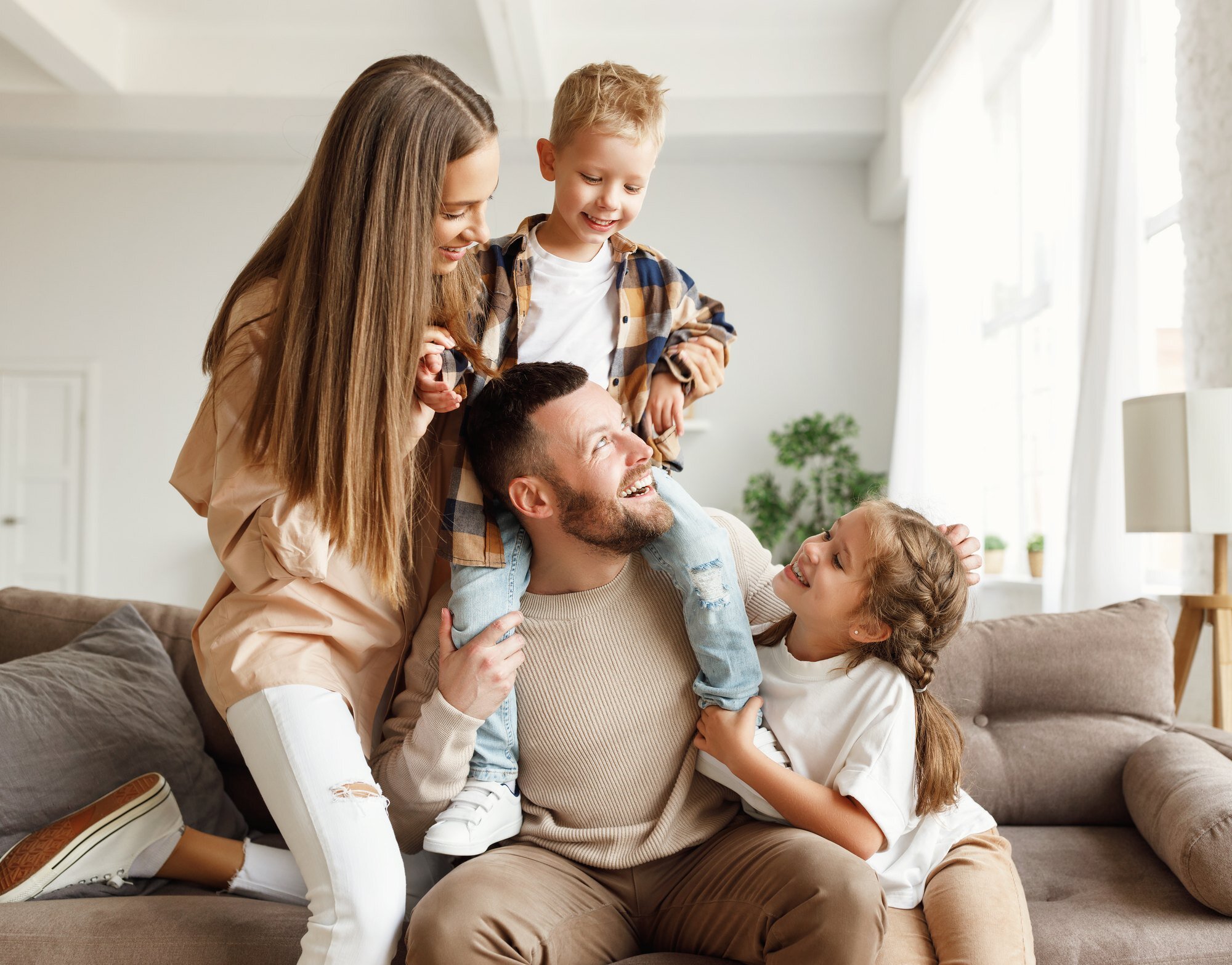 Parents and two children laughing together on a sofa at home