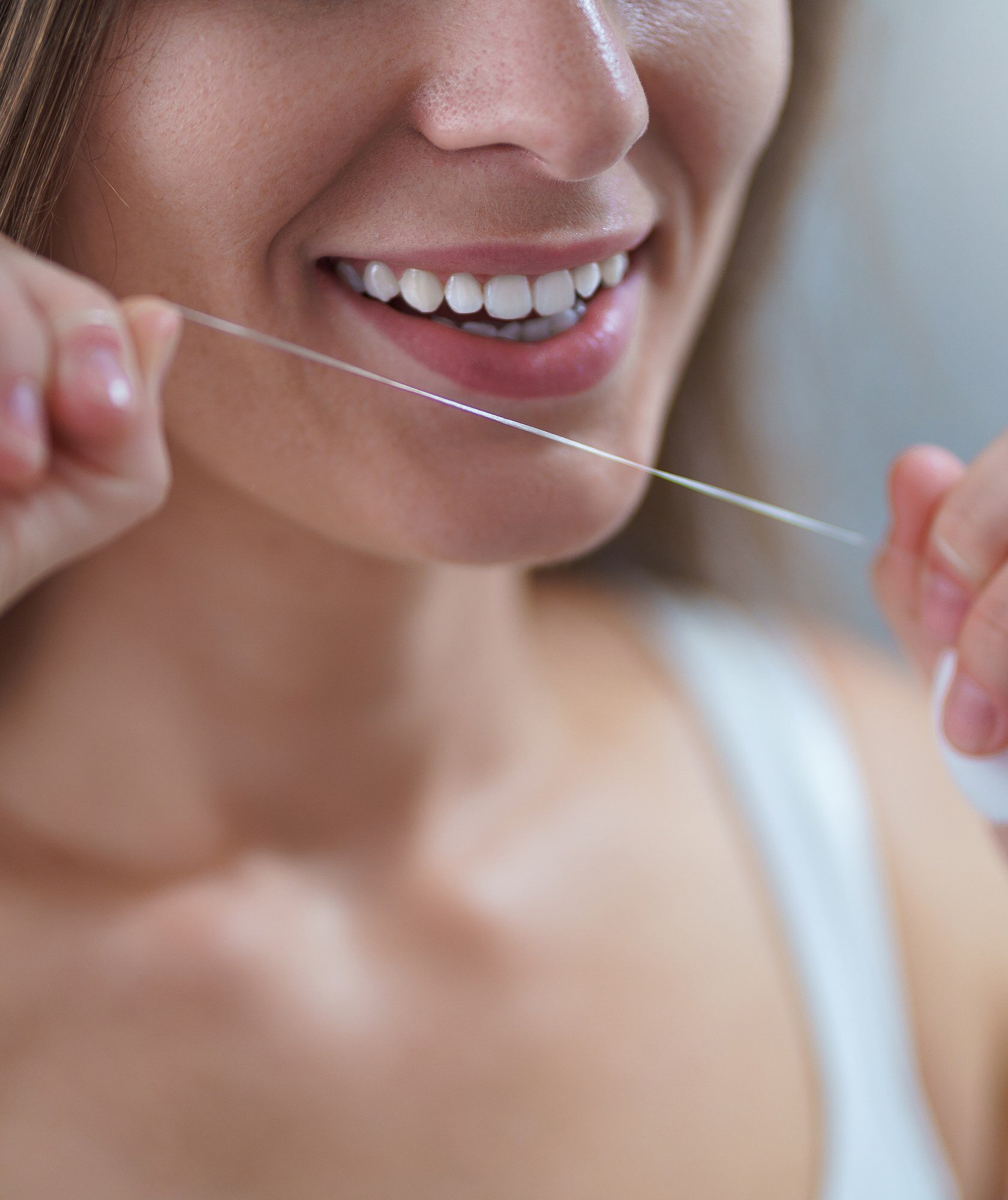 Woman flossing her straight, healthy teeth